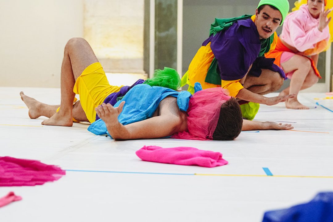 Contemporary dancers in colourful costumes performing indoors