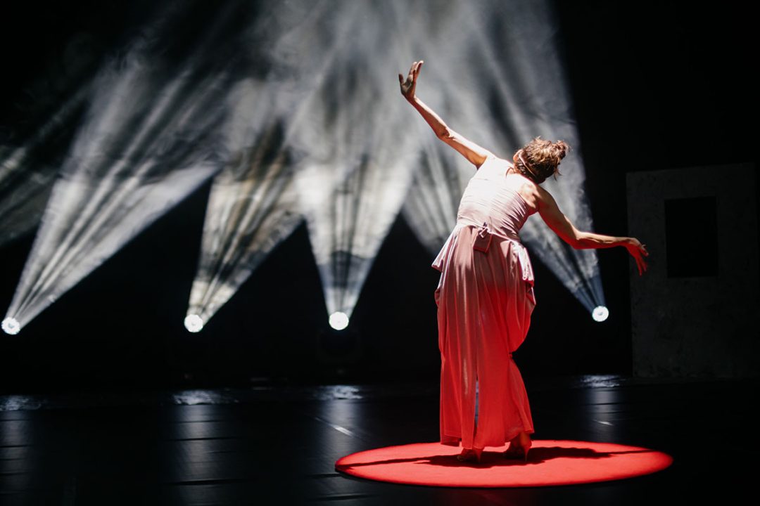 Contemporary dancer performing under dramatic stage spotlights