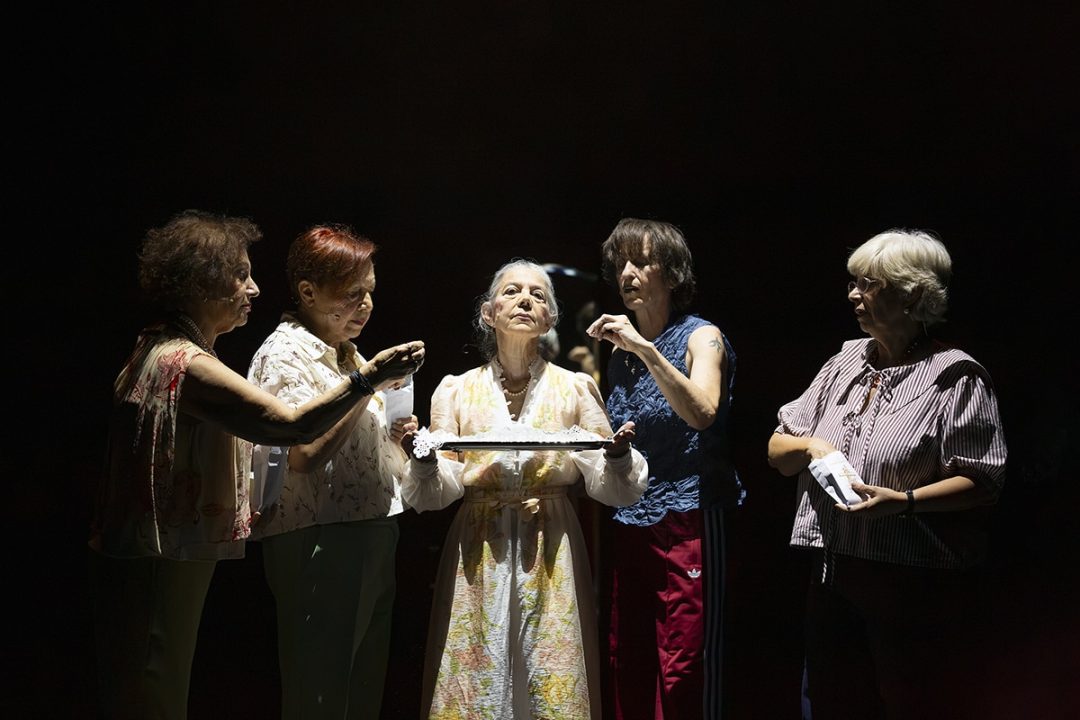 Five women performing under a dramatic spotlight on stage