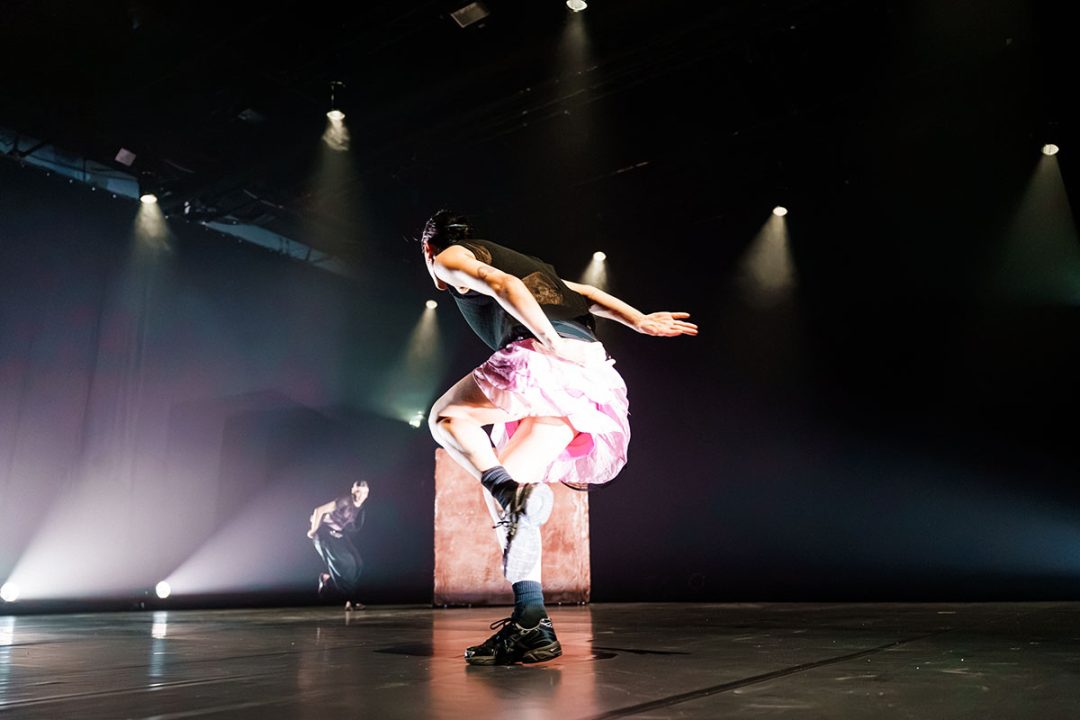 Dancer in pink skirt performing under dramatic stage lights