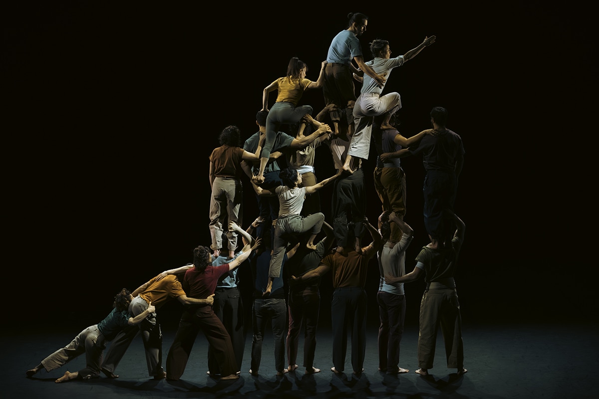 Dancers forming human pyramid on dark stage