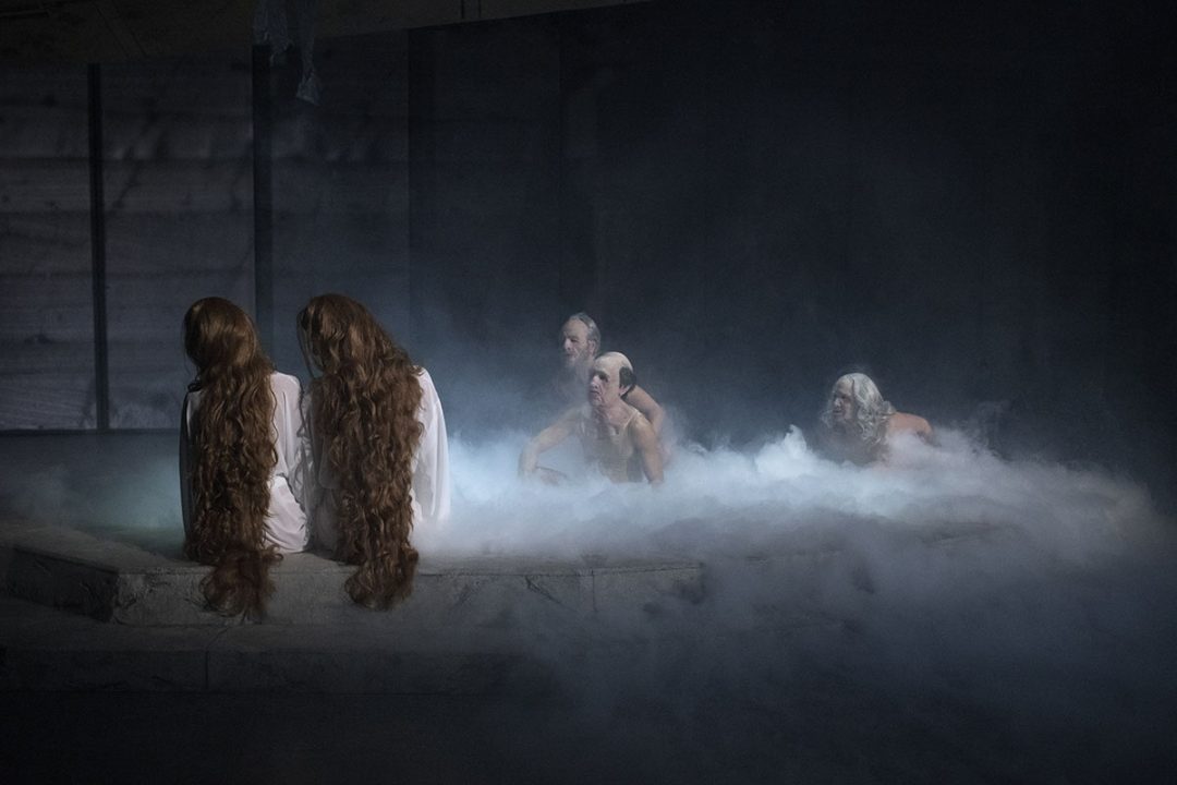 Long-haired figures beside ghoulish figures rising from a misty pool