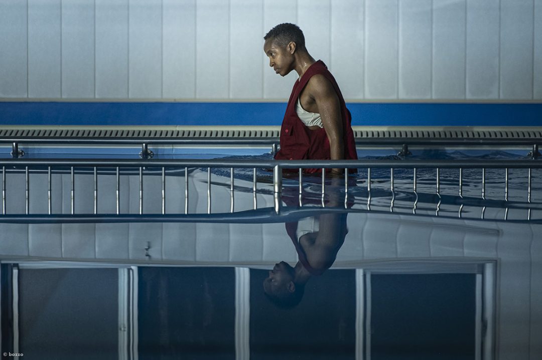 Person in red vest standing in an indoor swimming pool